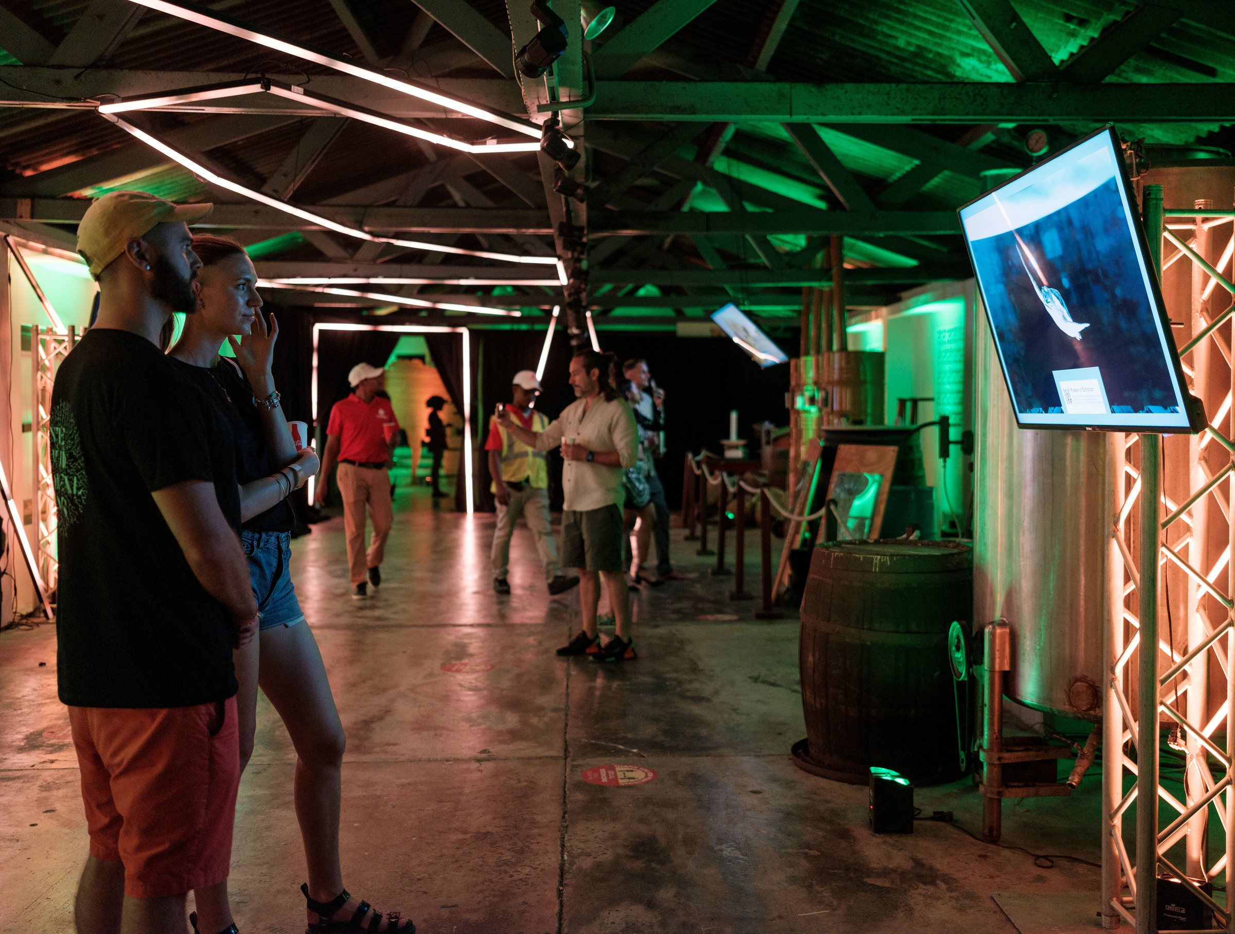 Visitors viewing a digital art installation lit green and orange