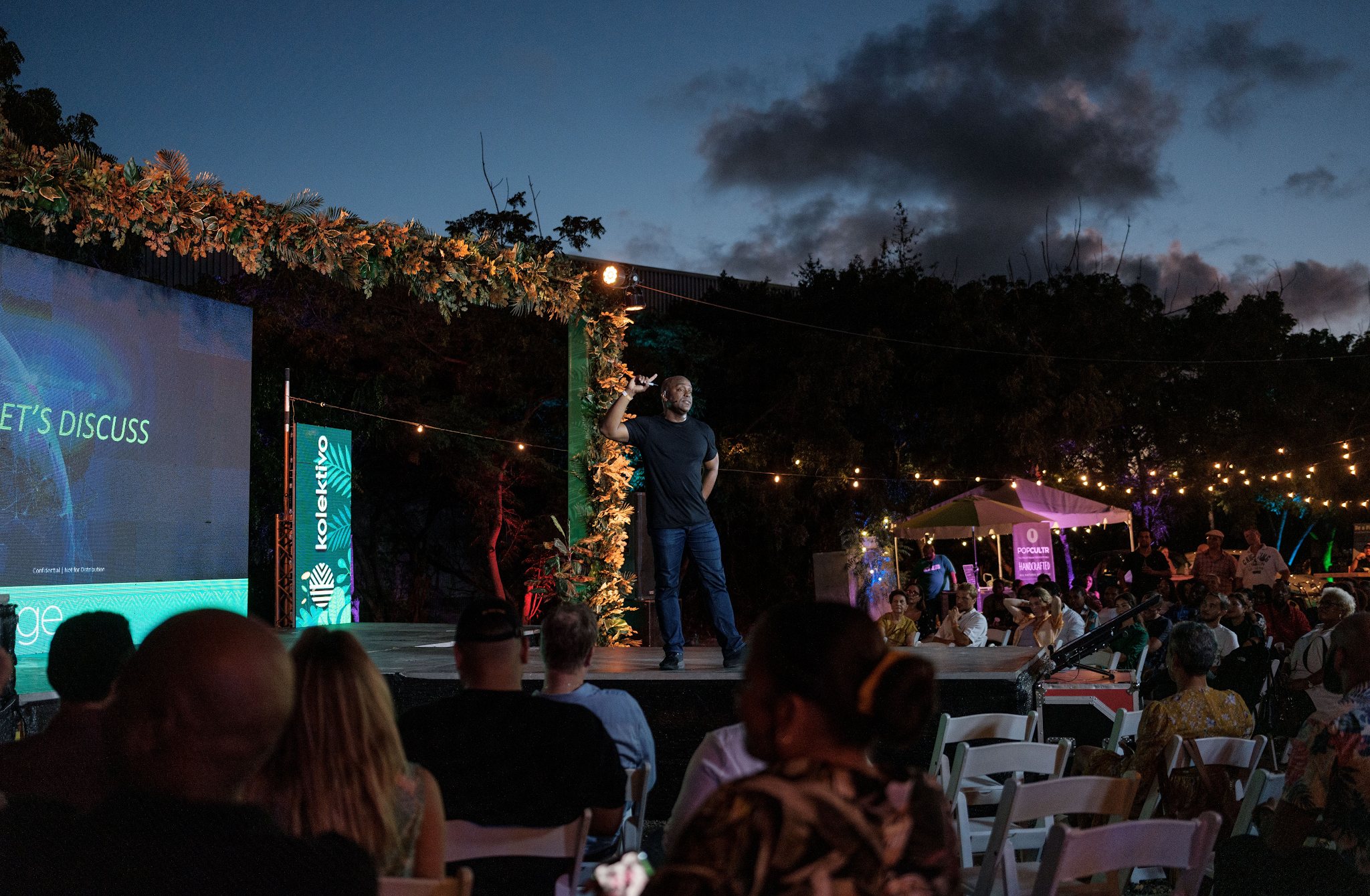 A speaker addressing an outdoor evening crowd at the Kolektivo Festival
