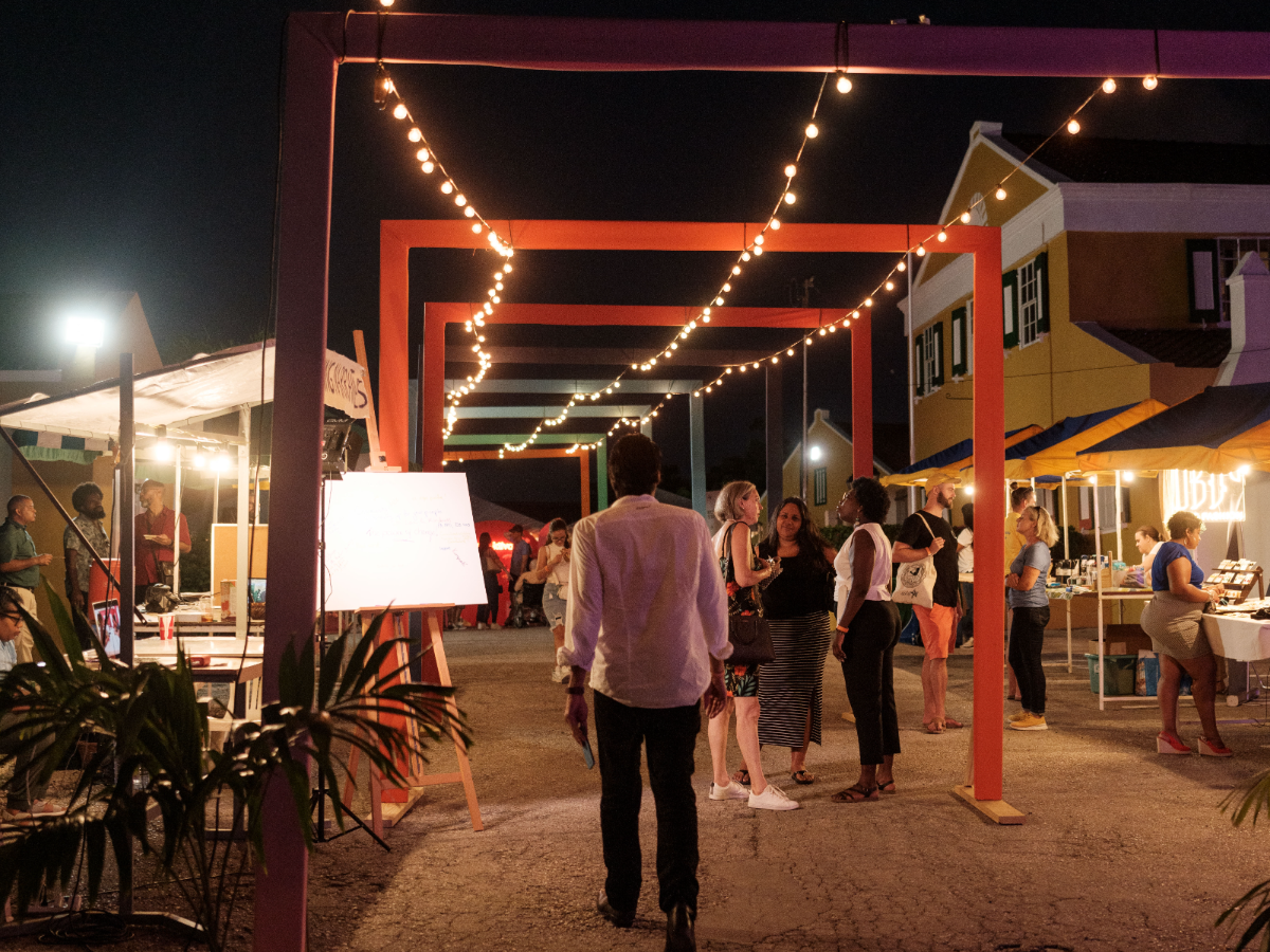 Kolektivo Festival: visitors under string lights between colourful arches at night